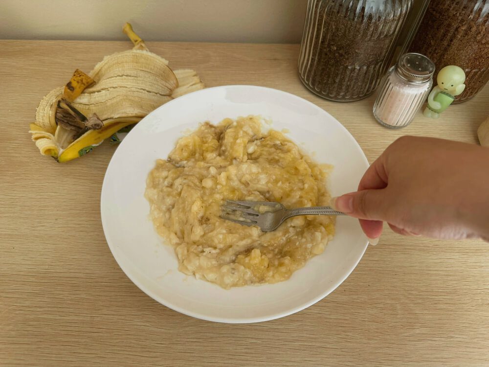 Bananen werden mit einer Gabel zerdrückt, erster Schritt für den Bananenkuchen-Teig.