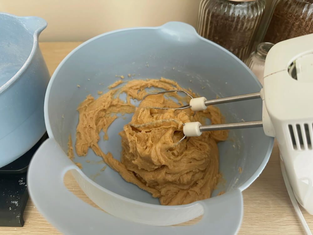 Ausgesiebte Trockenzutaten werden zum Teig hinzugegeben und mit Schneebesen verrührt, dritter Schritt für den Bananenkuchen-Teig.